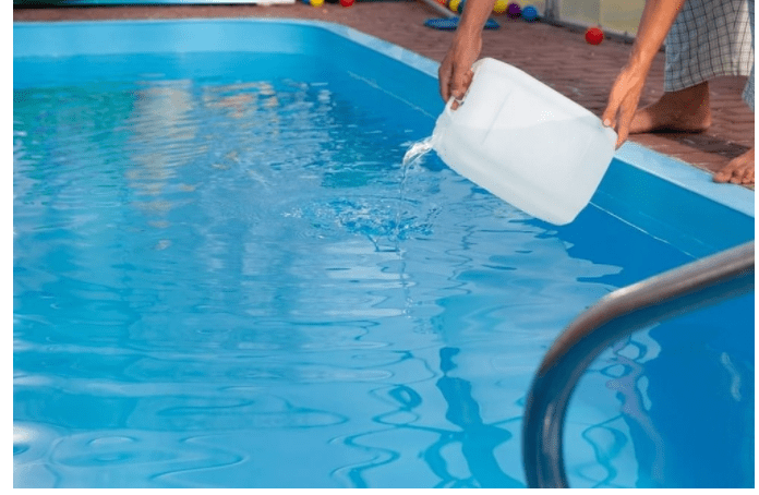 Person pouring water into a pool from a white container.
