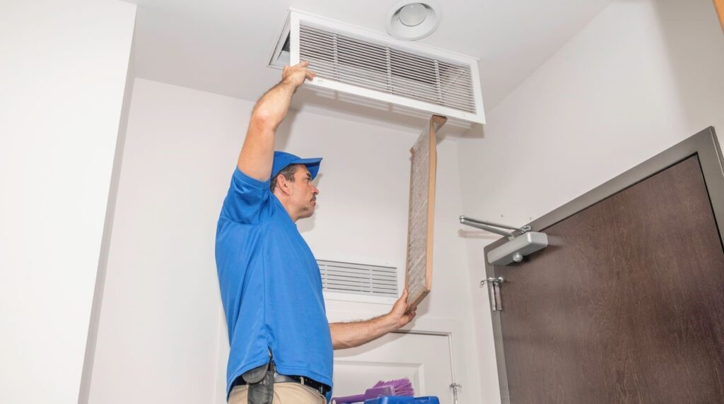 Technician removing or installing an air conditioner filter in a building.